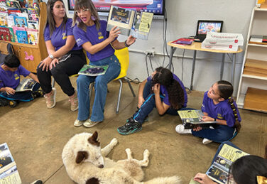 teacher reads book to circle of children in classroom