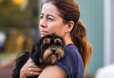 woman holds small dog solemnly