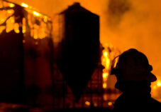silhouette of firefighter in front of burning farm