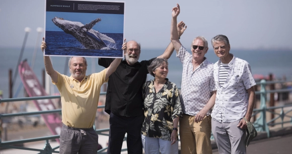 a group of five individuals standing on a pier to celebrate the 40th anniversary of the ban on commercial whaling