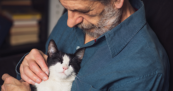 a man cradles and black and white cat