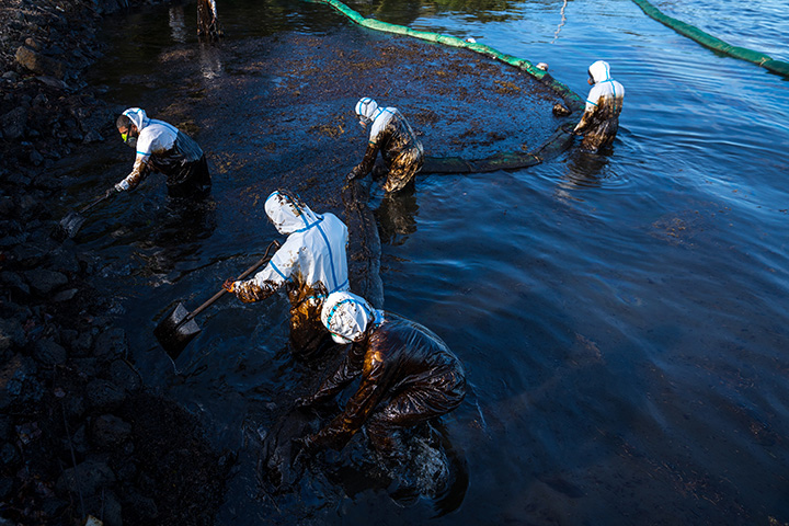 several people work to clean remnants of an oil spill
