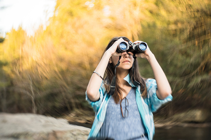 woman looks into distance using binoculars