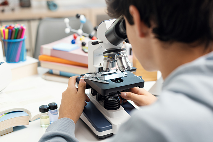 young student peers into a microscope