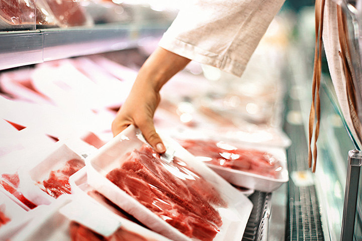 shopper reading label on meat packaging