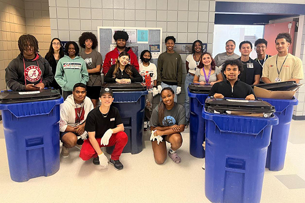 Several students, including Vjae Brown, past winner of the A Voice for Animals contest, stand proudly with recycling bins.