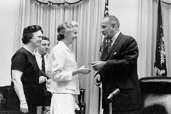President Johnson hands a pen to Christine Stevens.